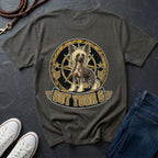 A grey t-shirt laid flat on a dark slate surface, featuring a graphic of a Chinese Crested dog inside a circular emblem with the text 'GOT YOUR 6'. White sneakers and blue jeans are styled around it with a leather strap in the corner.